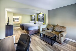 A modern hotel room with a bed, a sofa, a desk, and a chair.