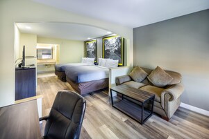 Una habitación de hotel moderna con una cama, un sofá, un escritorio y una silla.