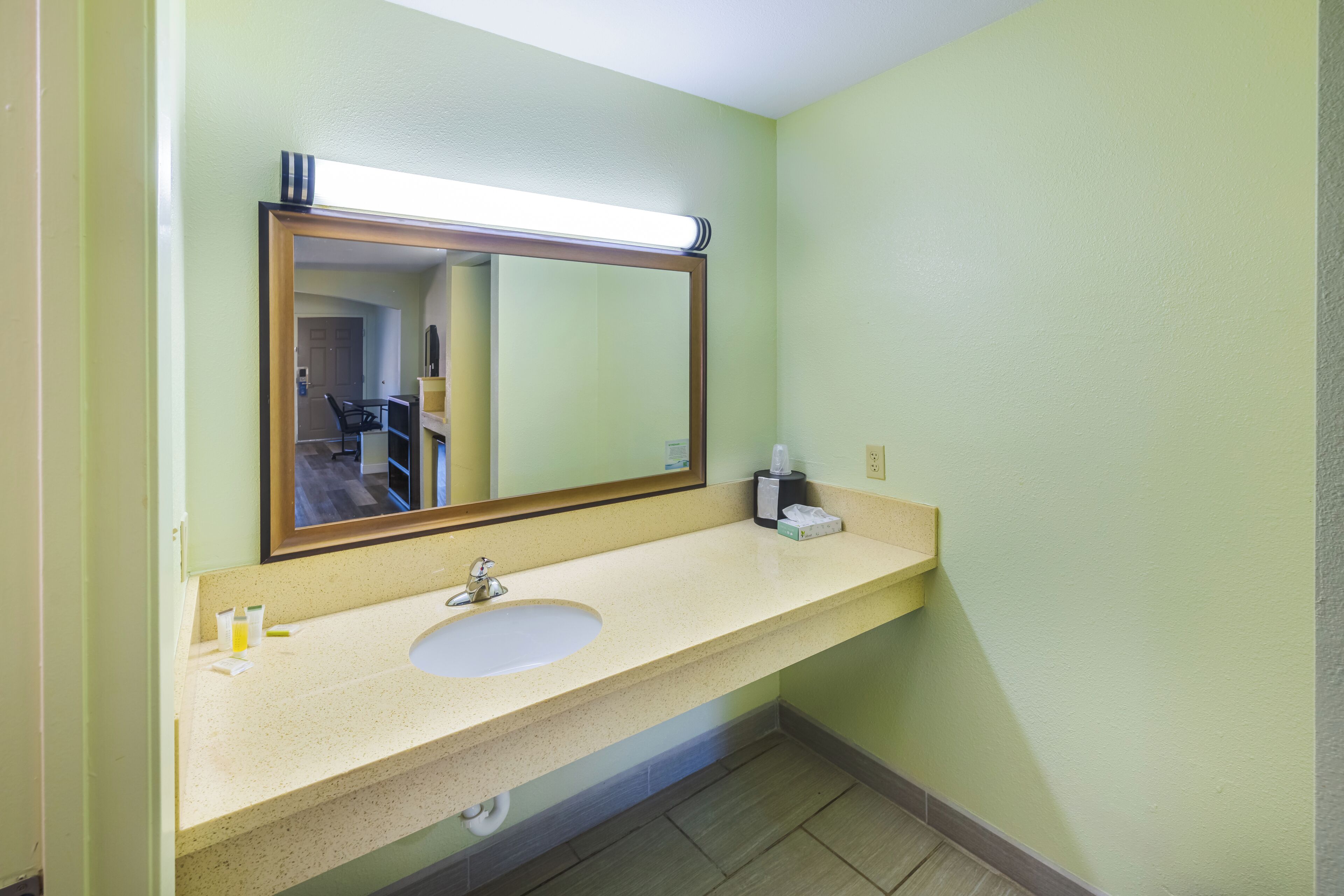 Een badkamer met een wastafel, spiegel en toiletartikelen.