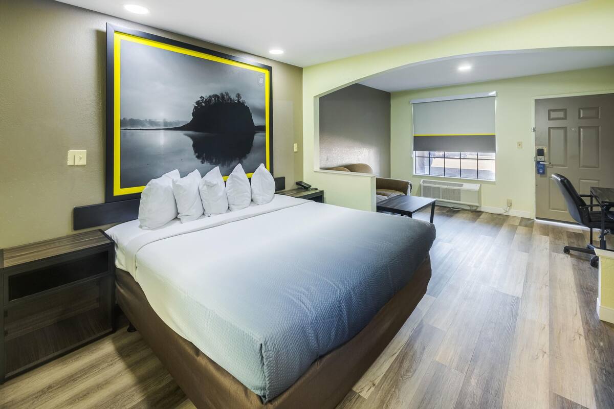 A modern hotel room with a large bed, a desk, and a chair.