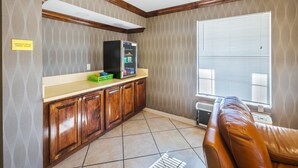 A kitchen with wooden cabinets, a refrigerator, and a window with blinds.