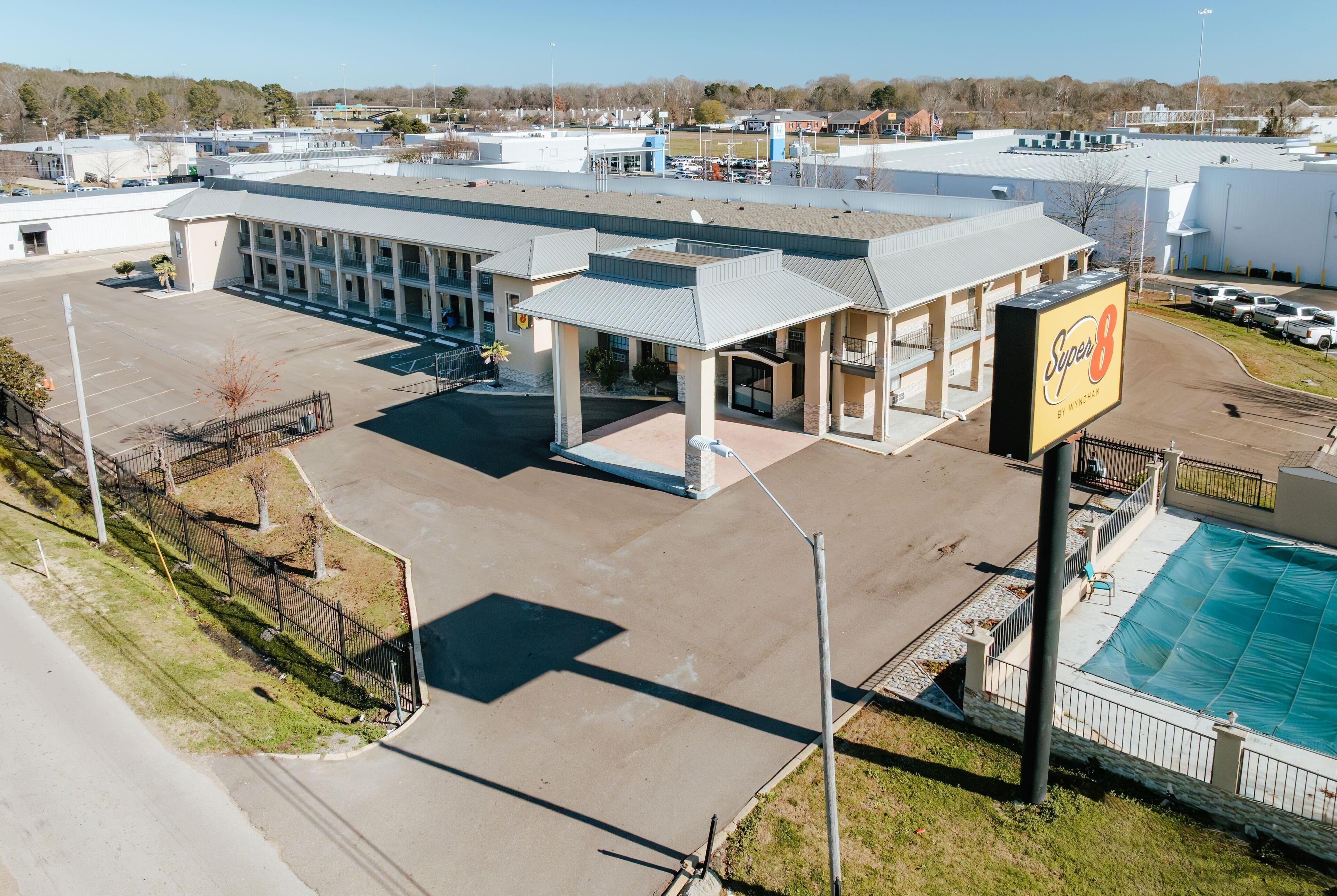 A commercial building with a large parking lot, a covered outdoor area, and a swimming pool.