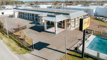 A commercial building with a large parking lot, a covered outdoor area, and a swimming pool.