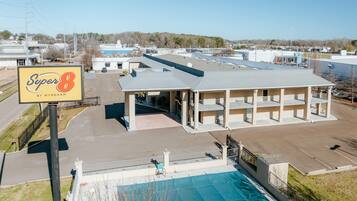 A multi-story building with a large sign reading "Super 8 by Wyndham" and a swimming pool in front.