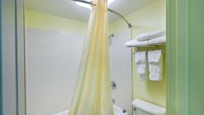 A bathroom with a shower curtain, a bathtub, a toilet, and a towel rack with towels.