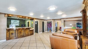 A spacious living area with a leather sofa, a wooden entertainment center, and a kitchen area with a refrigerator and a laptop.