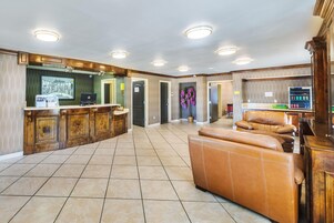 Un amplio espacio de sala con un sofá de cuero, un mueble de entretenimiento de madera y una zona de cocina con refrigerador y laptop.