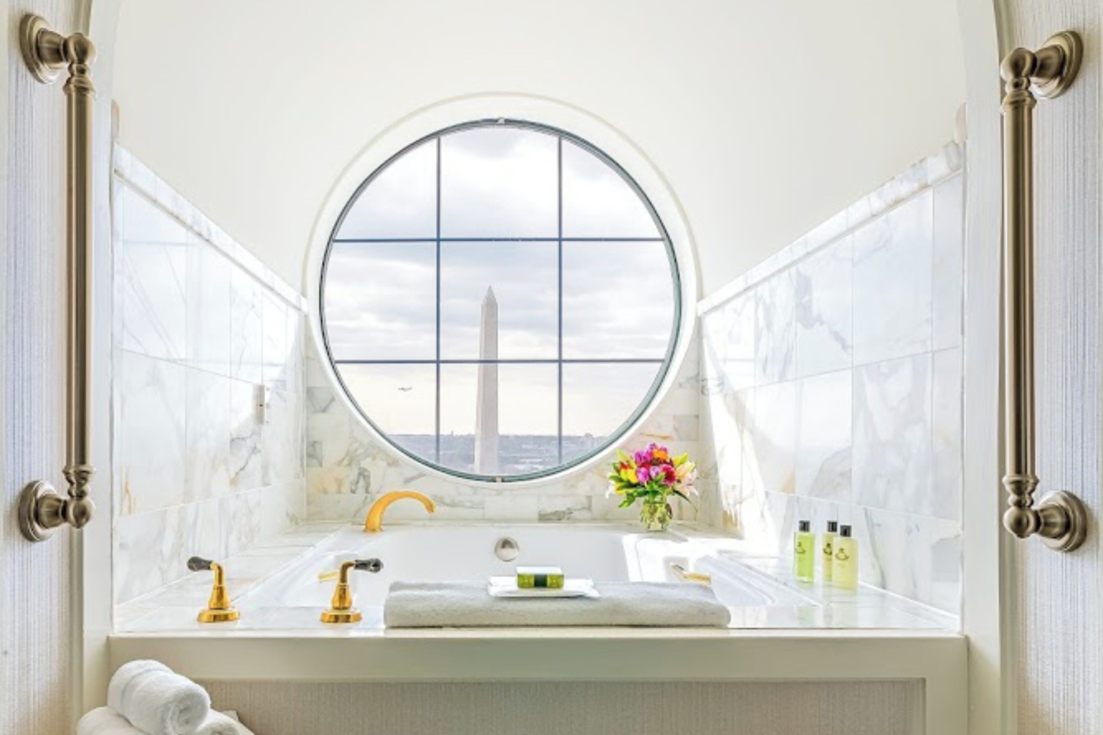 A bathroom with a large window, a bathtub, a sink, and a towel rack.