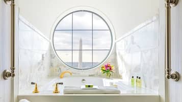A bathroom with a large window, a bathtub, a sink, and a towel rack.