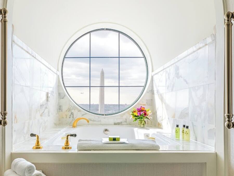 A bathroom with a large window, a bathtub, a sink, and a towel rack.