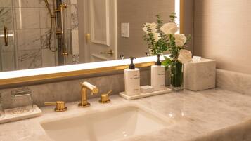 Un bagno con uno specchio grande, un lavabo con accessori dorati e articoli da bagno sul ripiano.