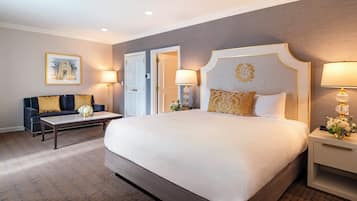 A hotel room with a large bed, a sofa, two bedside tables with lamps, and a framed picture on the wall.