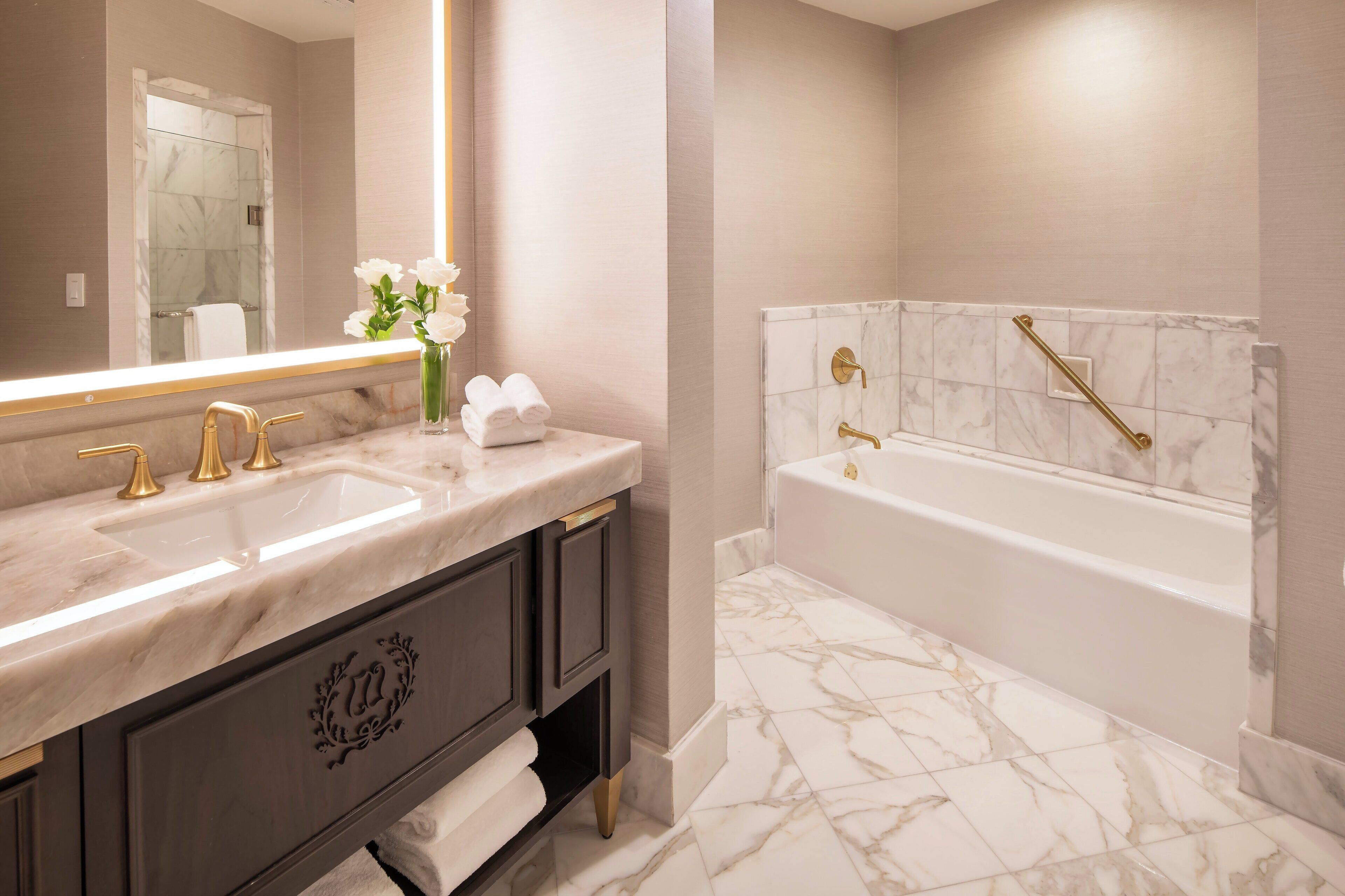 A modern bathroom with a marble vanity, dual sinks, a large mirror, and a freestanding bathtub.