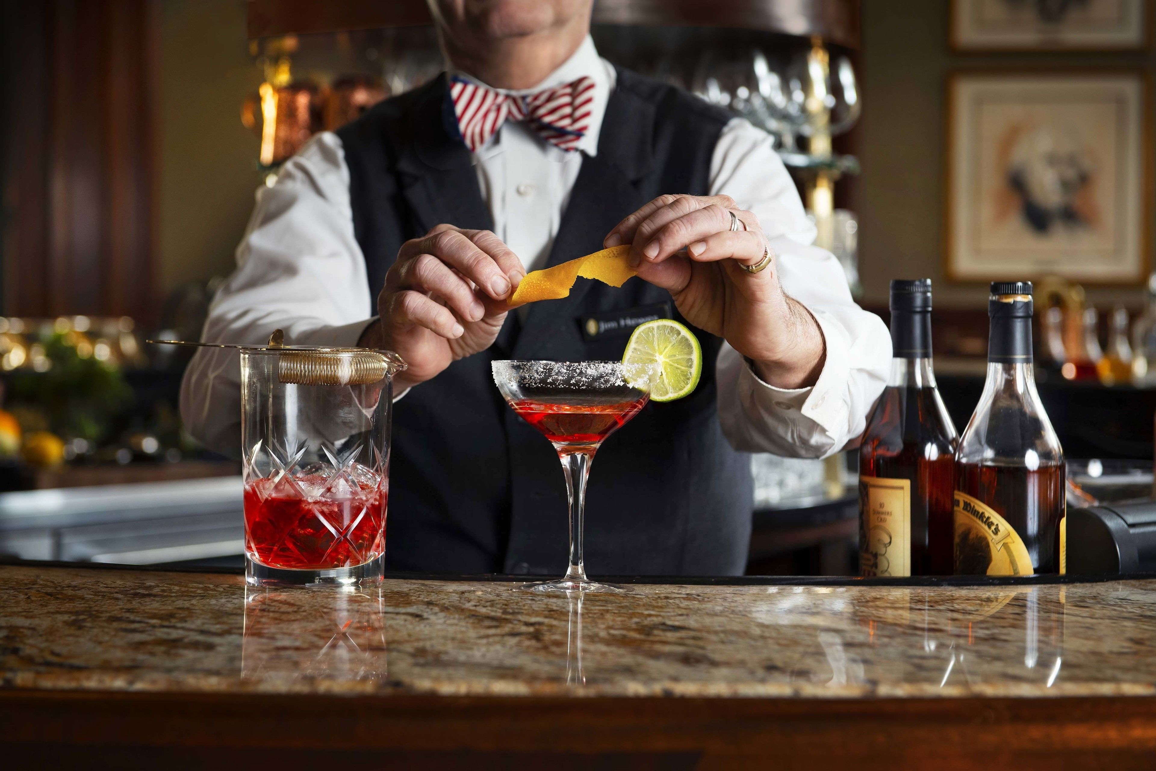 A bartender preparing a cocktail with a lime garnish.