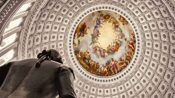 A grand, ornate ceiling with a central fresco surrounded by intricate geometric patterns.
