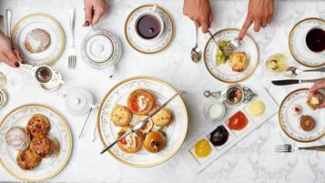 A table set with various pastries, a teapot, and multiple cups of tea.