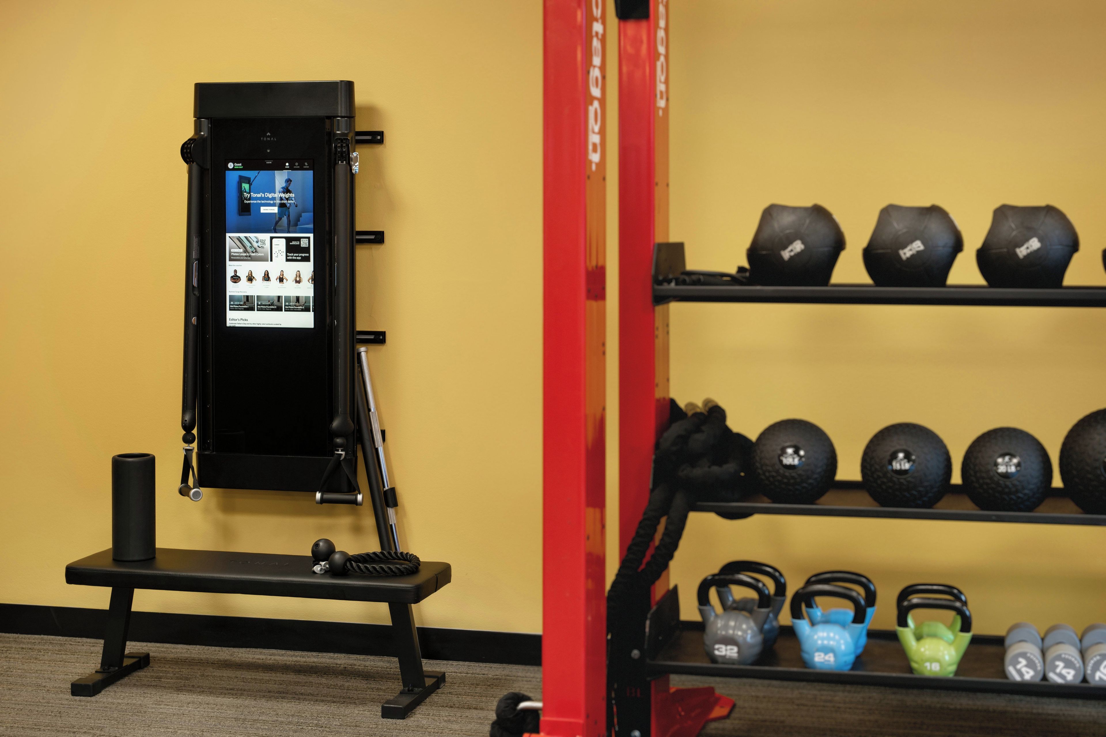 A gym with a weight machine, kettlebells, and dumbbells.