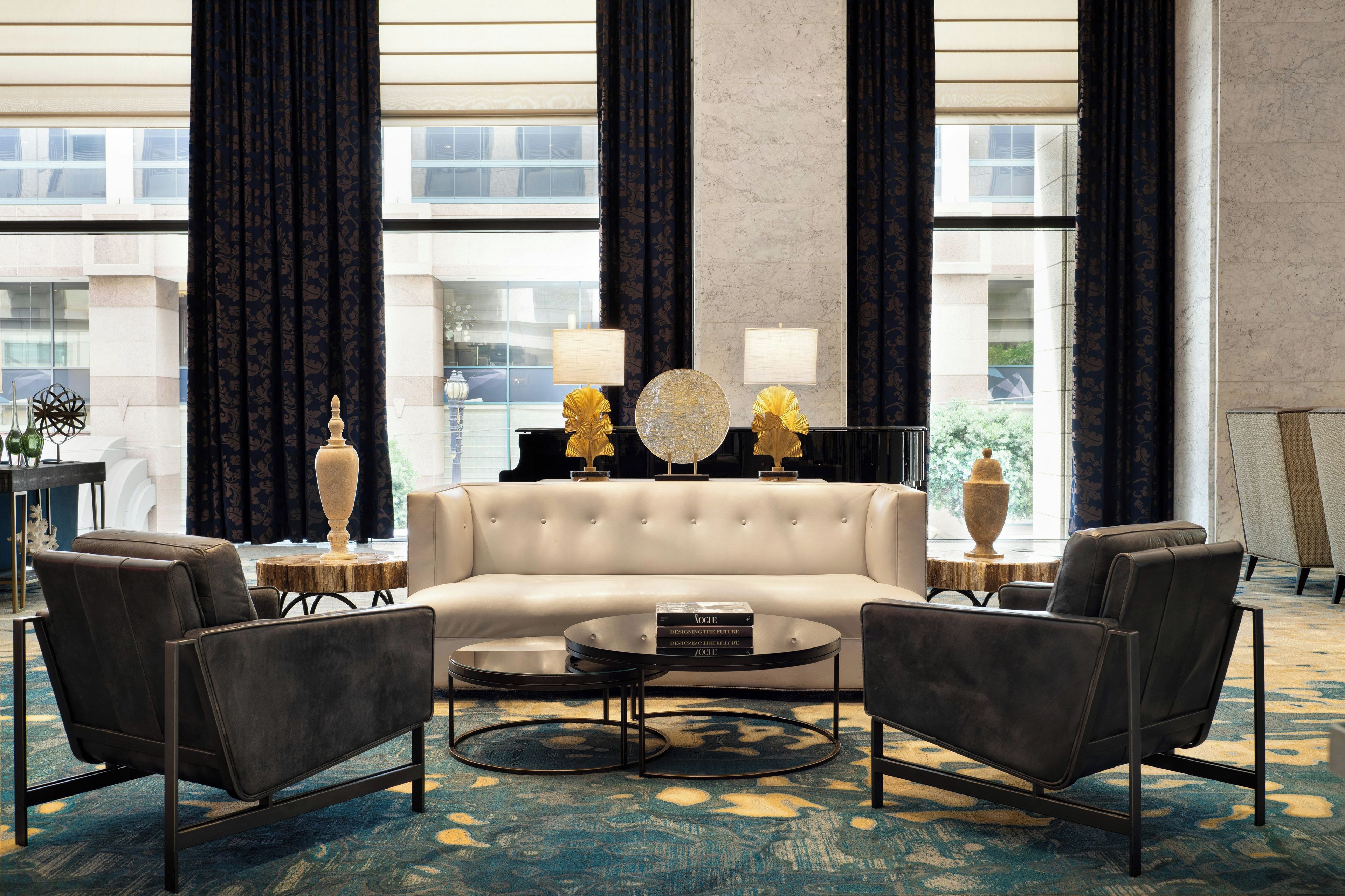 A modern living room with a sofa, two armchairs, a coffee table, and decorative lamps.