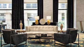 Una sala de estar moderna con un sofá, dos sillones, una mesa de centro y lámparas decorativas.