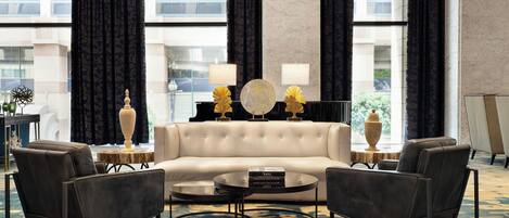A modern living room with a sofa, two armchairs, a coffee table, and decorative lamps.