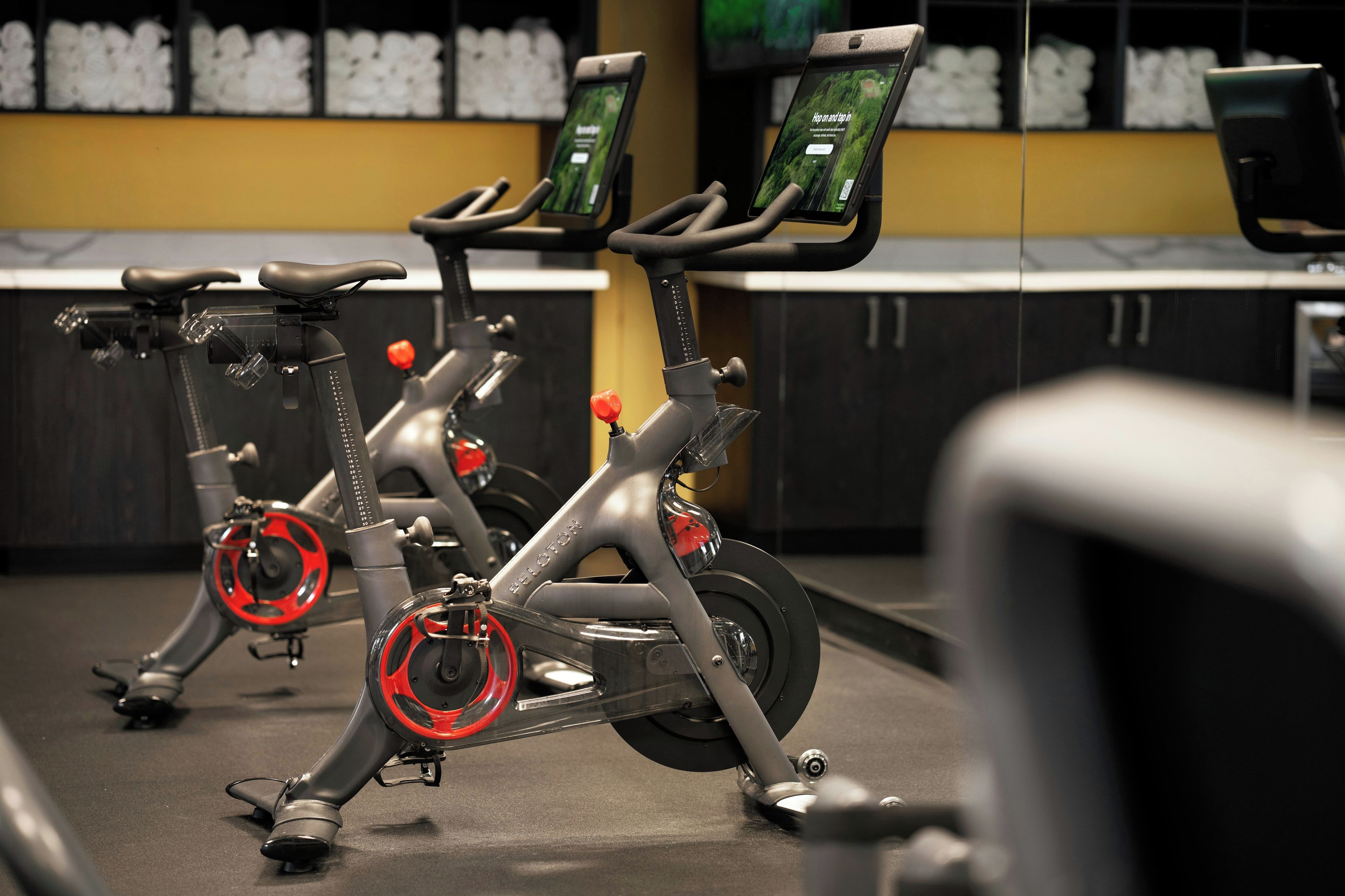 Stationary exercise bikes in a gym with a digital display screen on each.