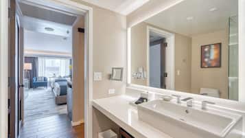 A modern bathroom with a large mirror, a white sink, and a shower area.