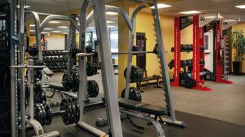 Une salle de sport équipée de matériel de musculation, de bancs et d’une structure octogonale rouge.