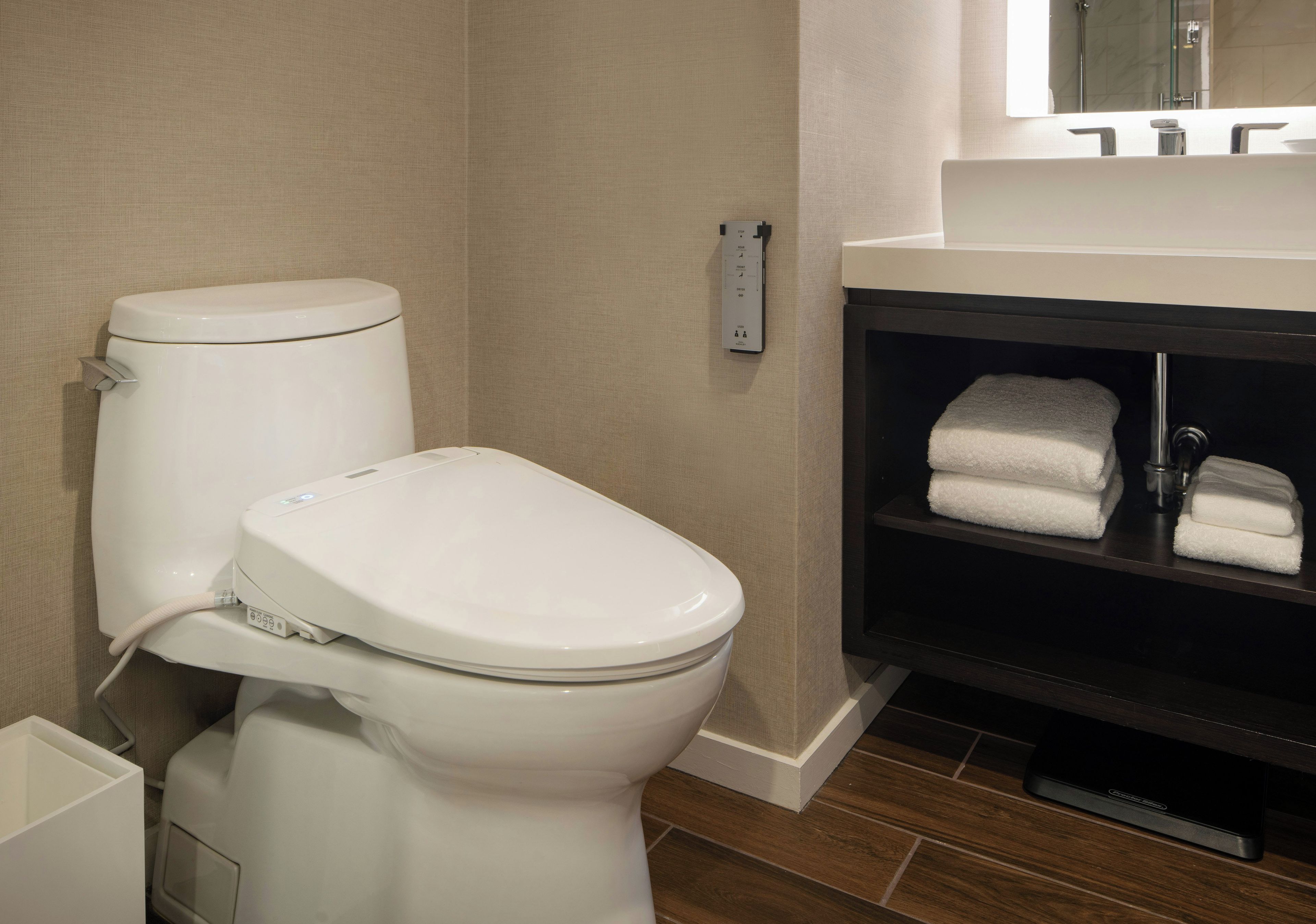 A modern bathroom with a toilet, a sink, and a towel rack.