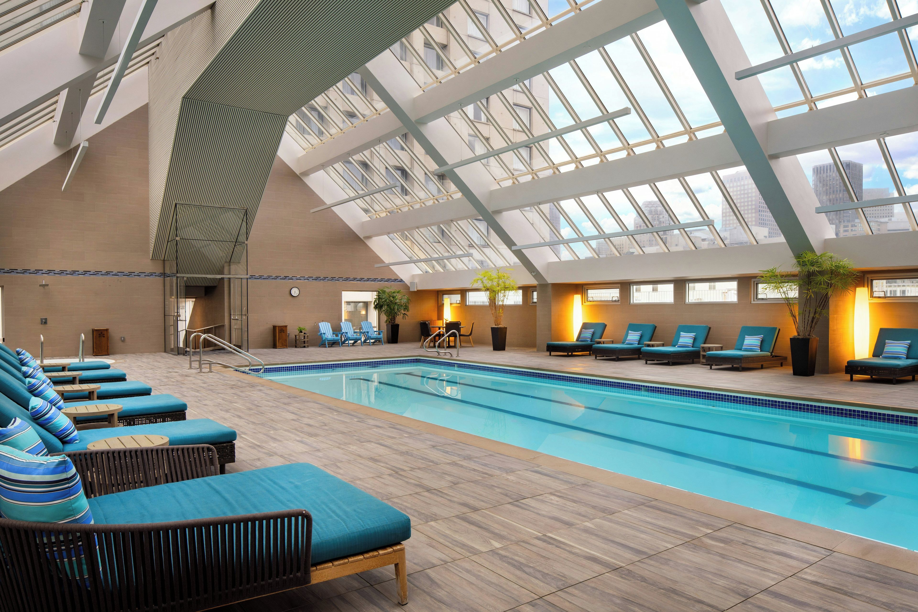 Una piscina interior con sillas de descanso y techo de cristal.