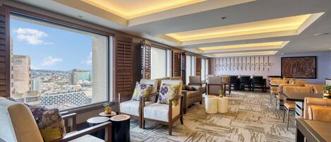 A spacious living area with a city view, modern furniture, and a patterned carpet.