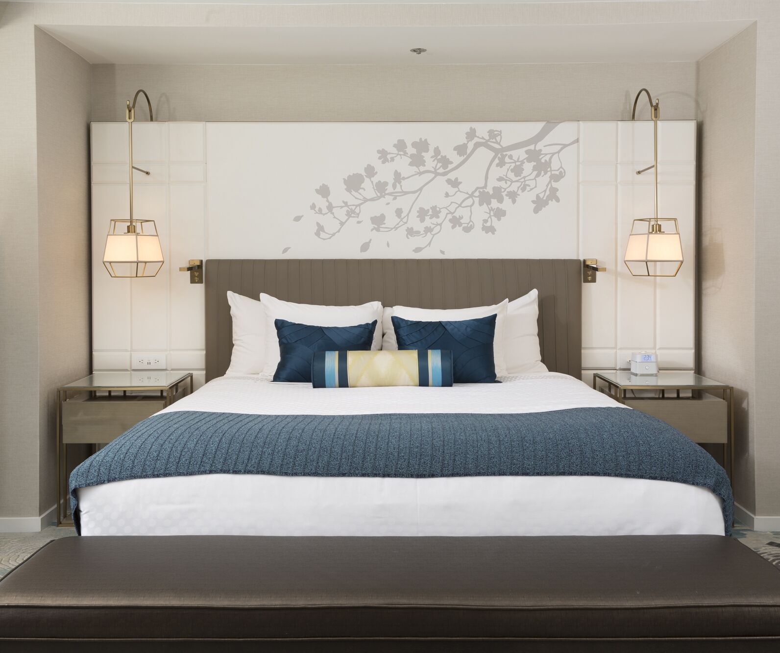 A neatly arranged hotel room with a large bed, two bedside tables, and a wall-mounted lamp.