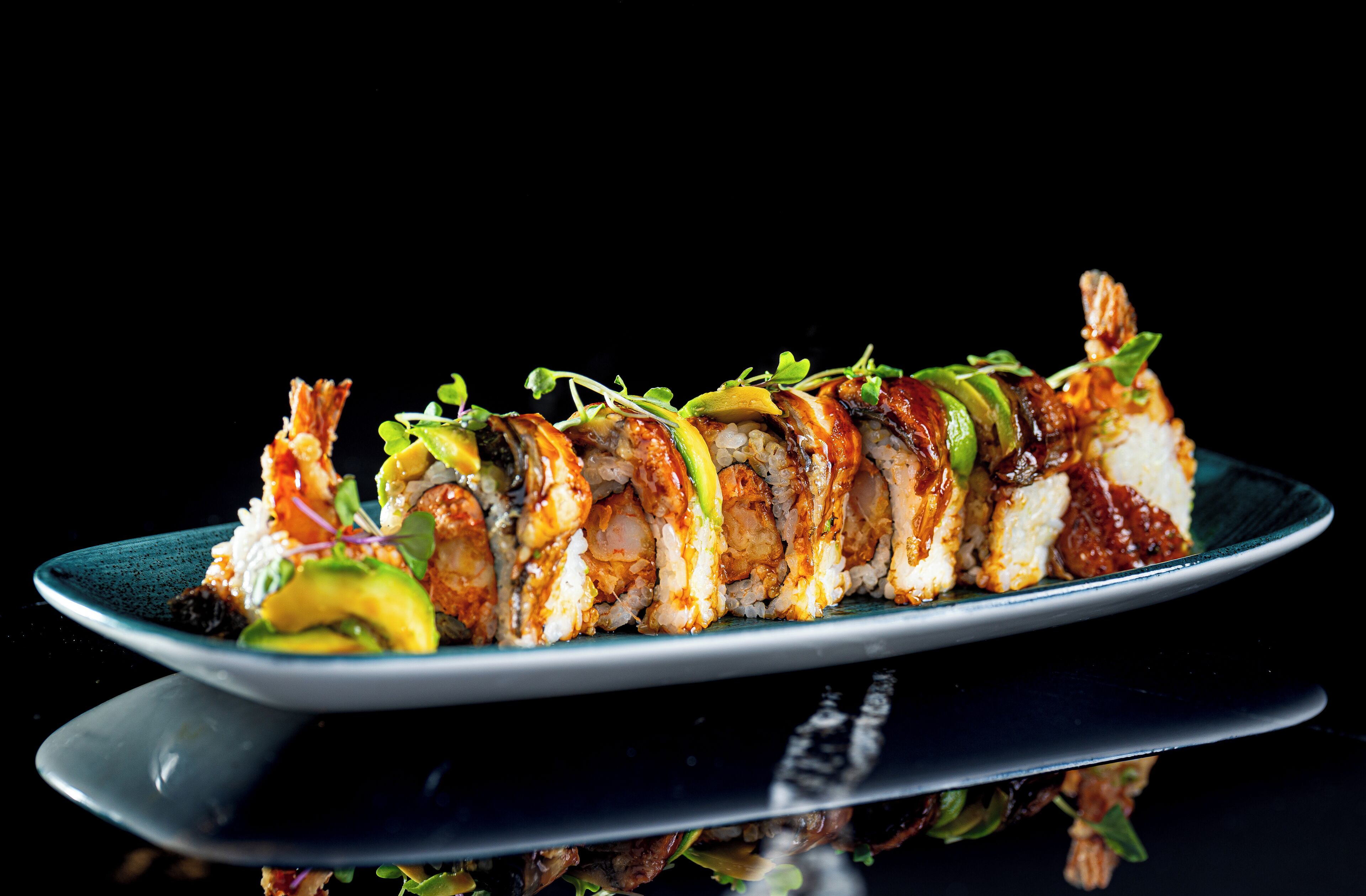 A sushi platter with various types of sushi on a dark plate.