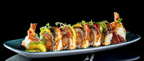 A sushi platter with various types of sushi on a dark plate.