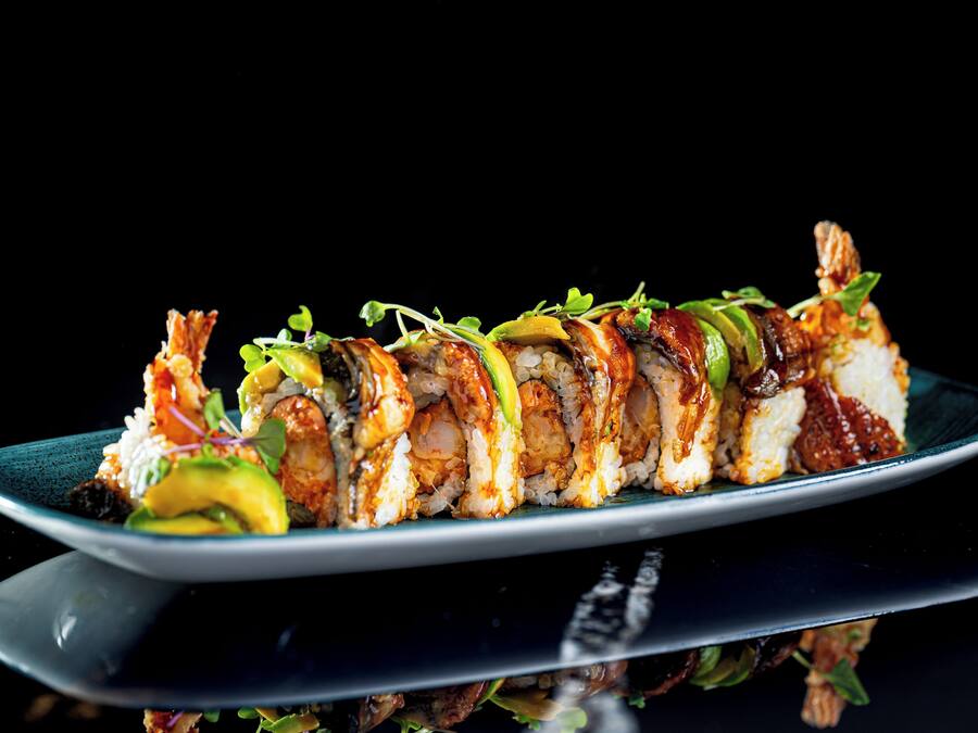 Ein Sushi-Teller mit verschiedenen Sushi-Sorten auf einer dunklen Platte.