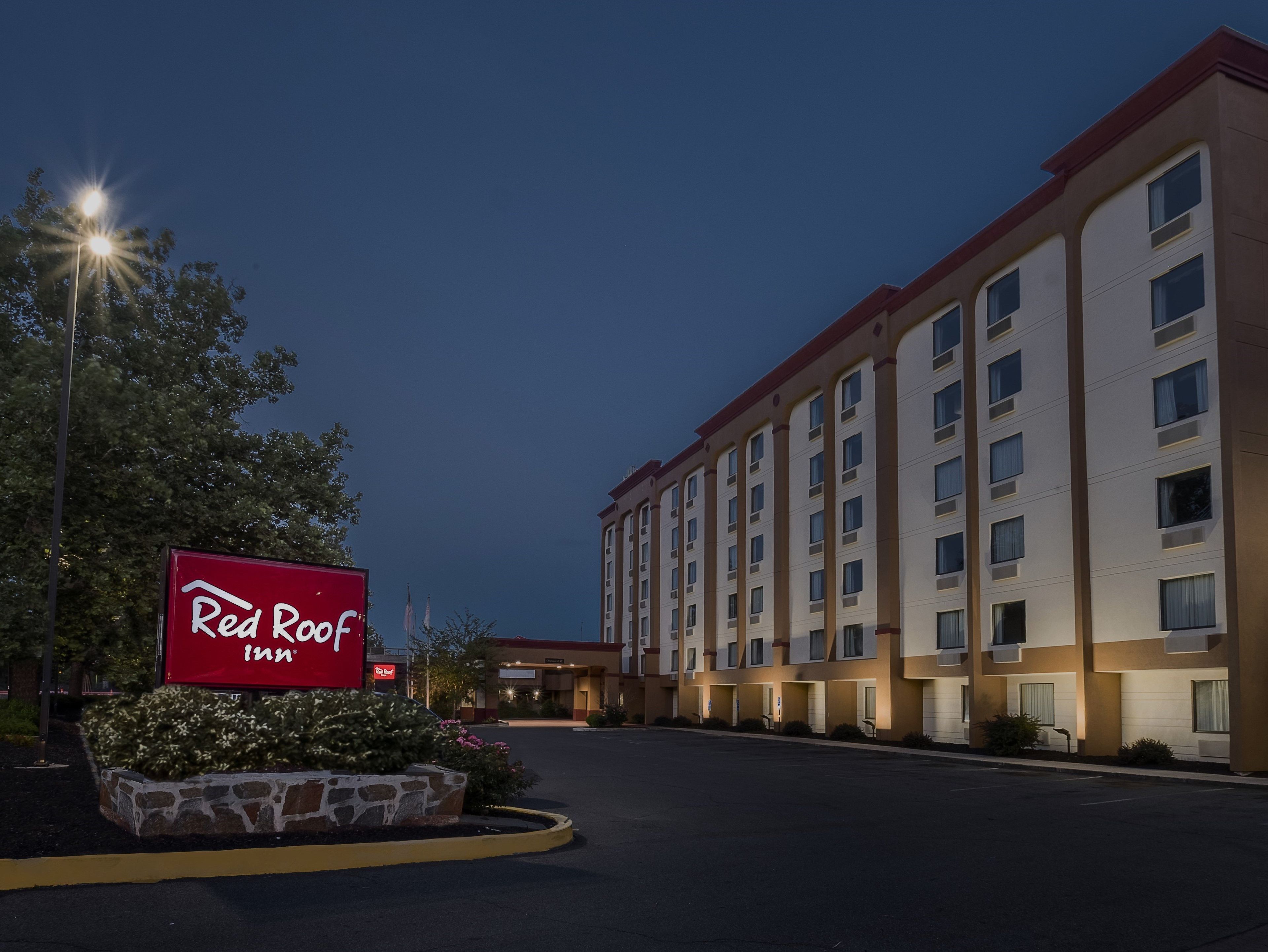 Un hotel Red Roof Inn con un amplio estacionamiento y un letrero.