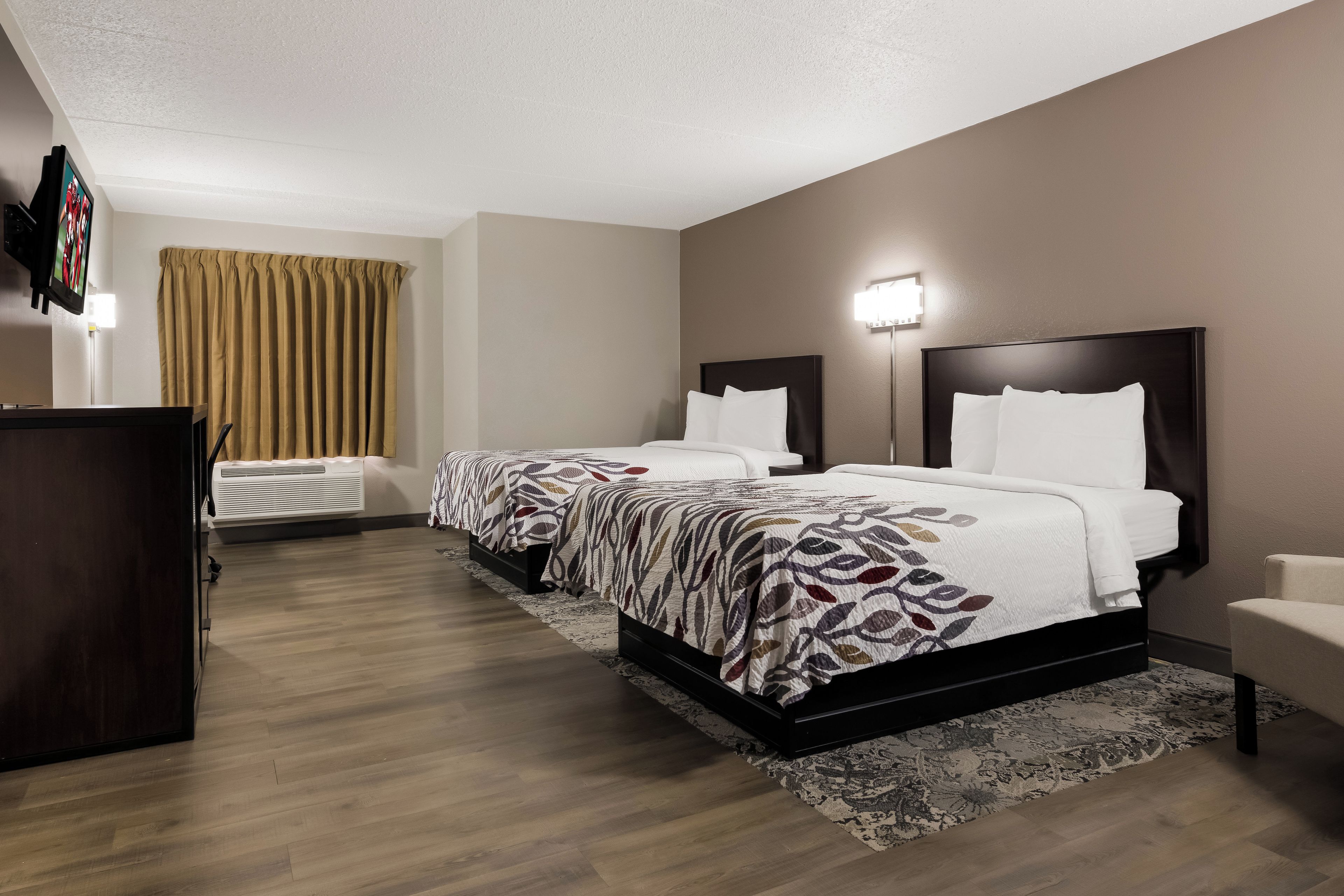 Habitación de hotel con dos camas, un televisor de pantalla plana, un escritorio y un ventanal grande.