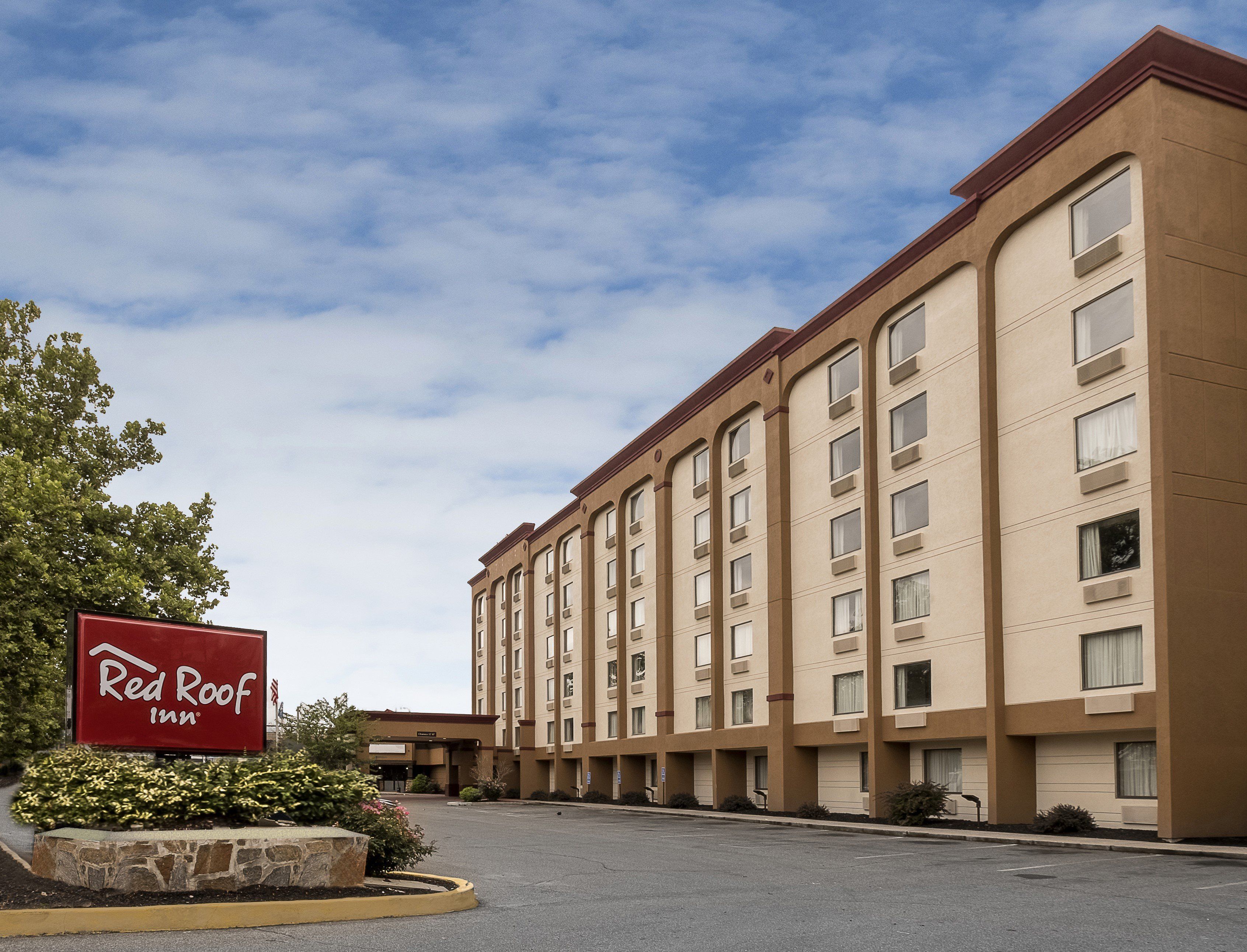 Hotel Red Roof Inn com estacionamento e céu claro.