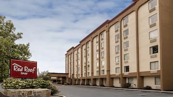 Hotel Red Roof Inn com estacionamento e céu claro.