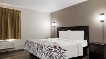 Quarto de hotel com cama, mesas de cabeceira, luminária na parede e janela com cortinas.