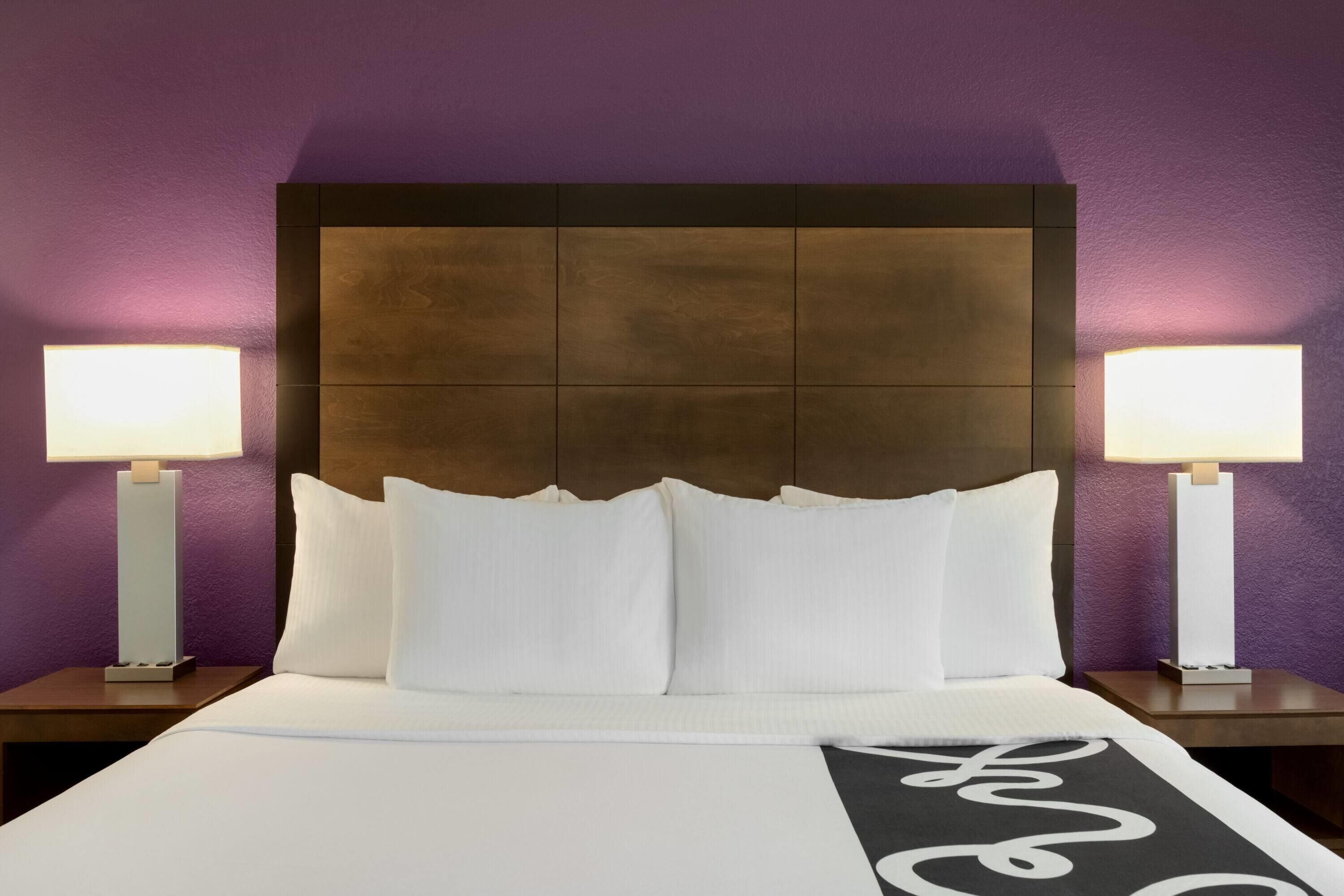 Ein Hotelzimmer mit einem großen Bett, zwei Nachttischlampen und einem Kopfteil mit einem besonderen Design.