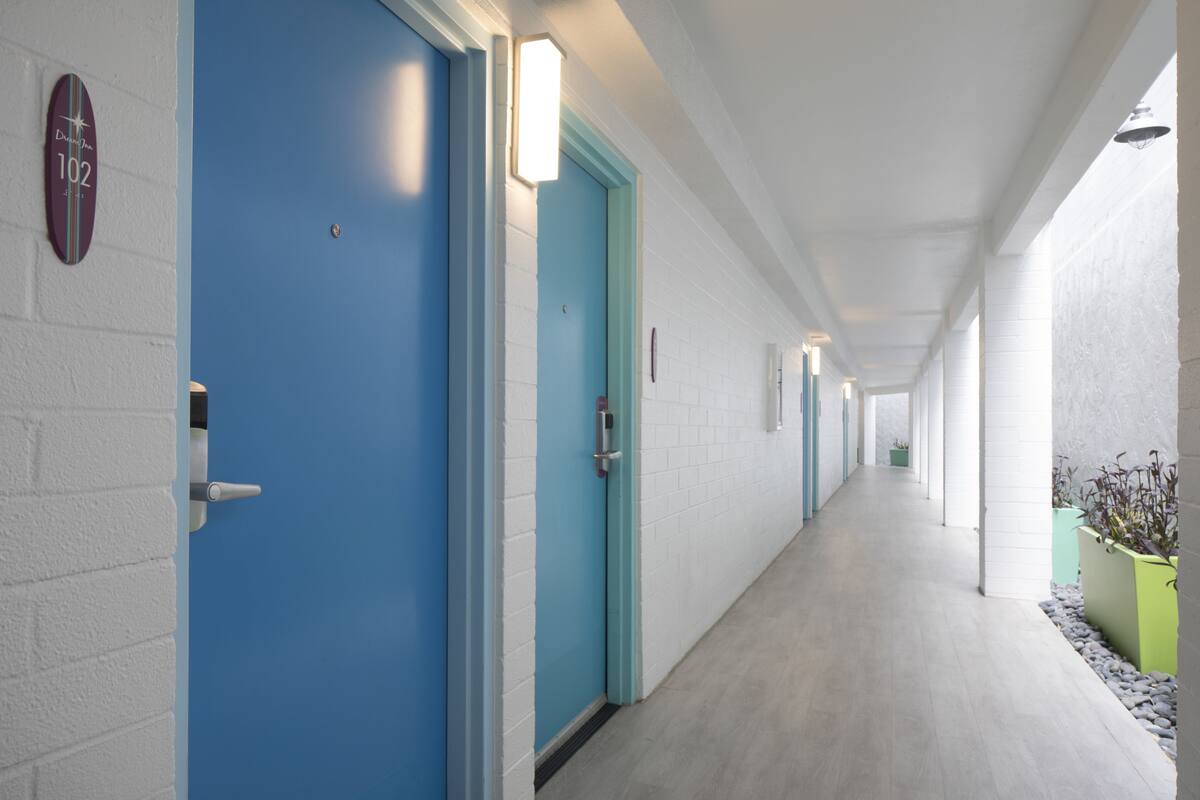 A hallway with blue doors, white walls, and a light-colored floor.