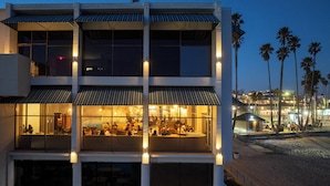 A modern building with multiple dining areas, large windows, and a view of the beach and palm trees. - Dream Inn Santa Cruz (Santa Cruz)