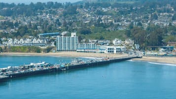 Een kustplaatsje met een pier die het water in reikt, een strand en een groot hotel met meerdere verdiepingen en balkons met uitzicht op zee.