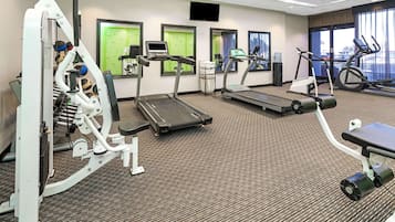 A hotel fitness center with treadmills, elliptical machines, and a weight bench.