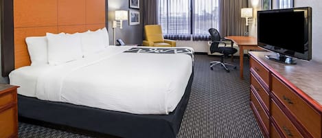 Habitación de hotel con una cama grande, un televisor, un escritorio y una silla.