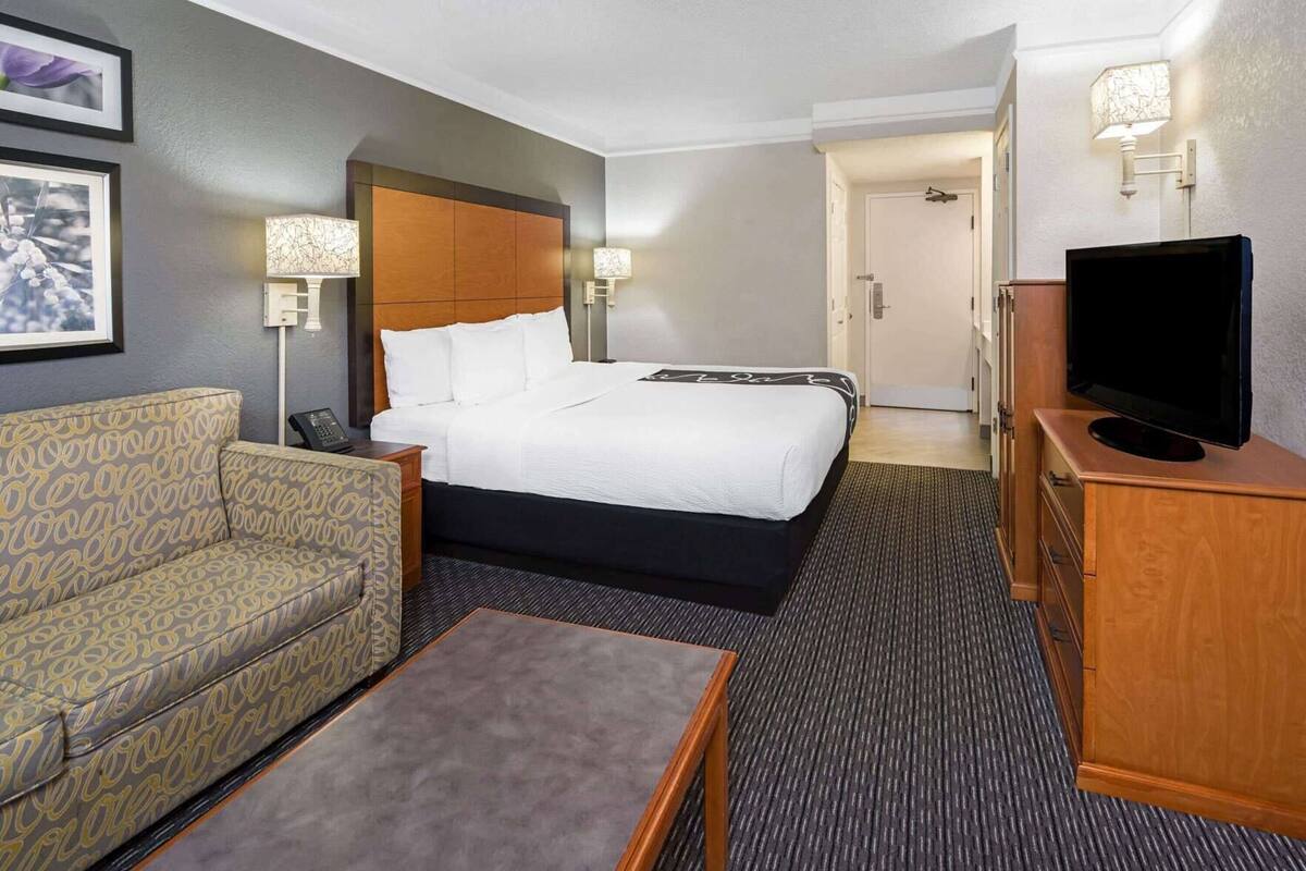 Una habitación de hotel con cama, sofá, televisor y escritorio.