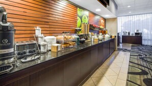 Zona de desayuno de hotel con barra libre, que incluye cafetera, tostadora y diversos alimentos.