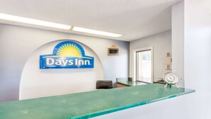 Ein Empfangsbereich mit einem Days Inn Schild, einer Uhr und einem gerahmten Auszeichnungsschild an der Wand.