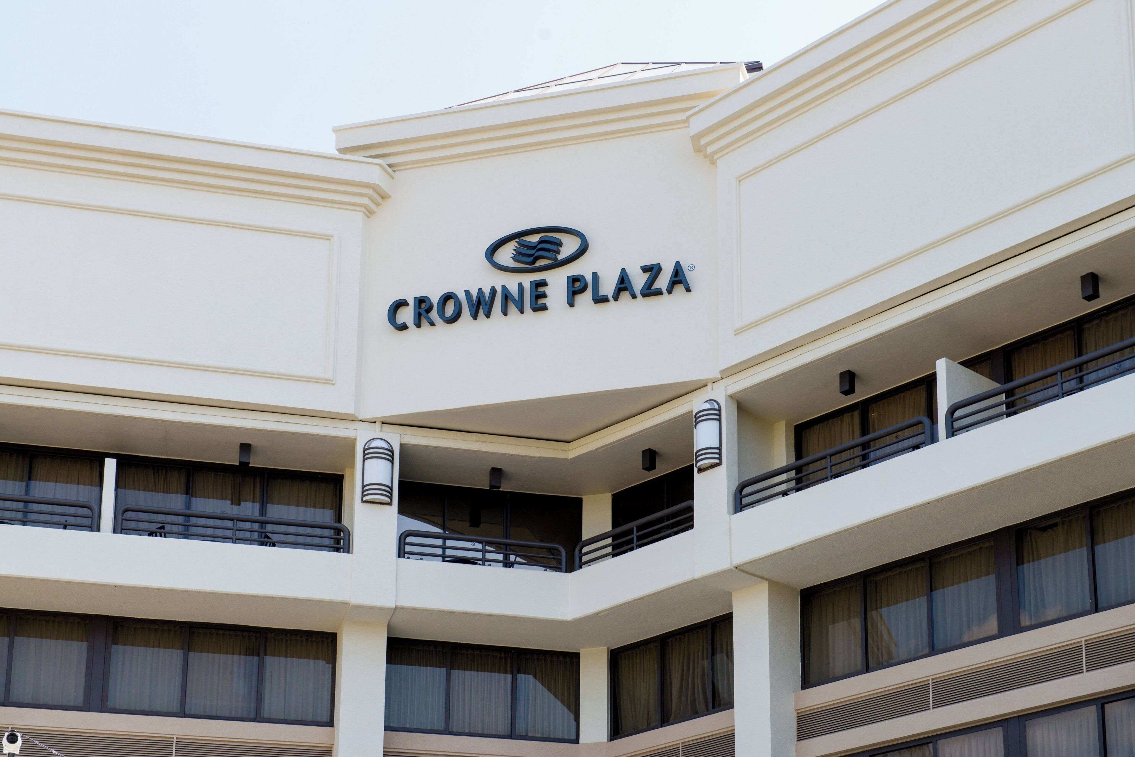 A building with a sign reading 'CROWNE PLAZA' and multiple balconies.