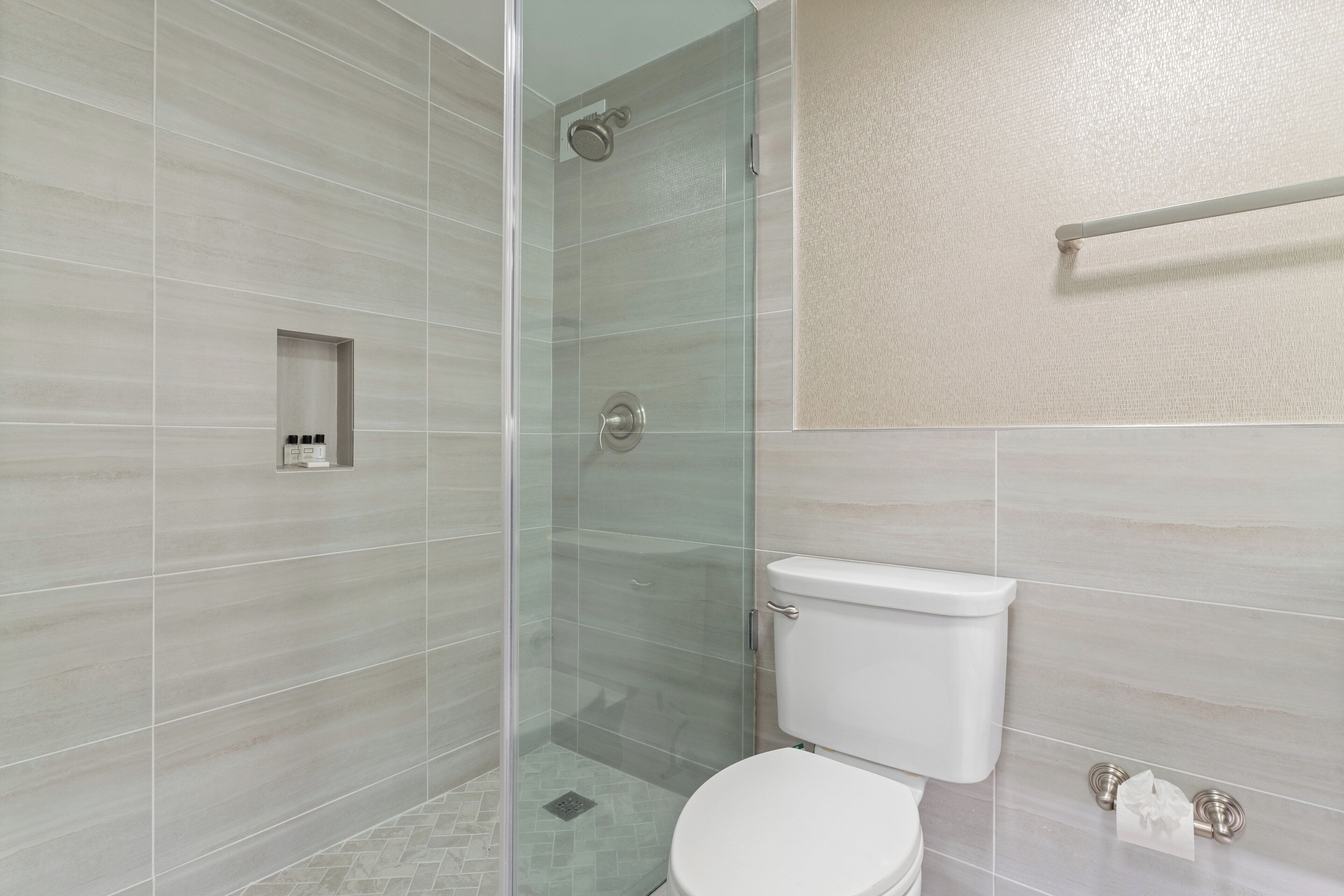 A modern bathroom with a glass-enclosed shower, a toilet, and a towel rack.